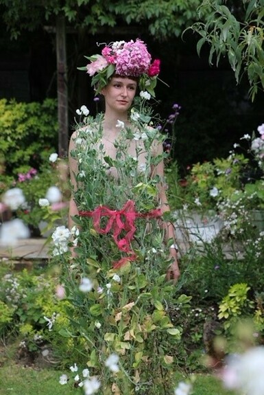 Photo of a model wearing a floral headdress, standing in front of foliage, giving the appearance that the pants are her clothes