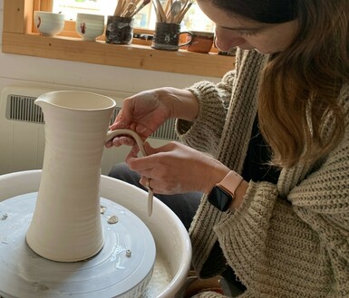 Photo of a woman with short brown hair making a jug from clay