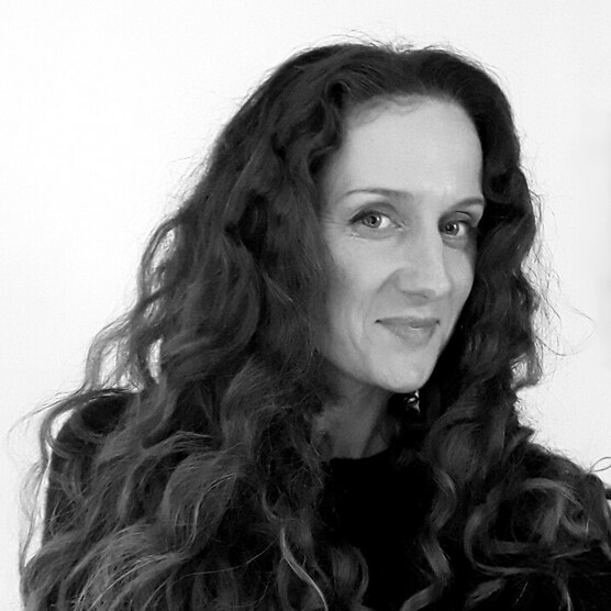 Black and white photo of a woman with long dark curly hair, smiling at the camera