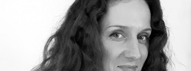 Black and white photo of a woman with long dark curly hair, smiling at the camera