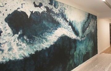 Artwork displayed on a wall of what looks like the sea, and whitewash caused by waves