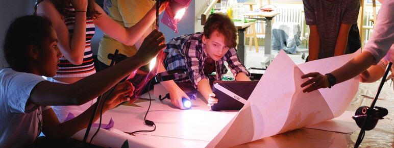 Teenagers gather round a makeshift photo studio experimenting with light