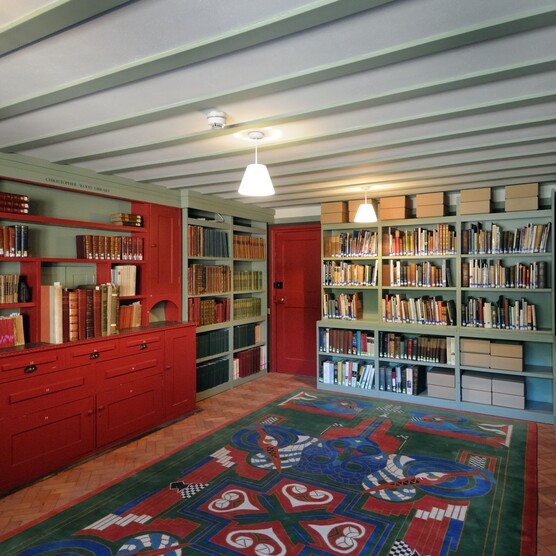 a green and red painted room lined with bookshelves