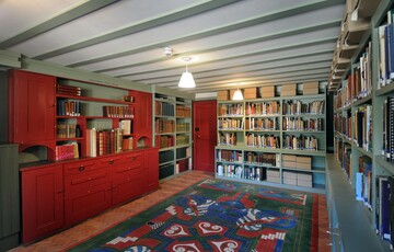 a green and red painted room lined with bookshelves