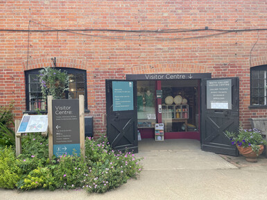 The entrance has two black doors, the building is red brick, with signs outside