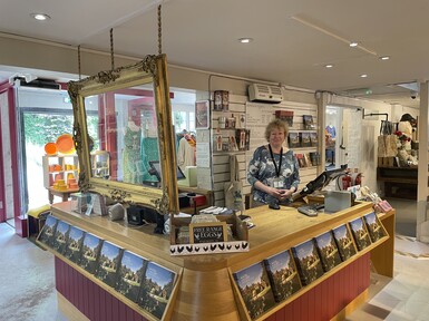 The desk is wooden, a staff member smiles behind the till