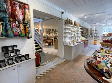 The shop is white with a stone tiled floor. There are tables covered with products and displays on the walls