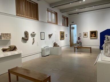 Temporary exhibition space set up for A Fragmented Legacy, the walls are white and pieces of sculpture and artwork line the walls