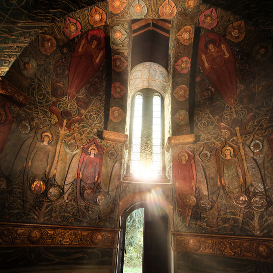 The Chapel interior with the sun shining through a window, casting the interior into gloom in comparison