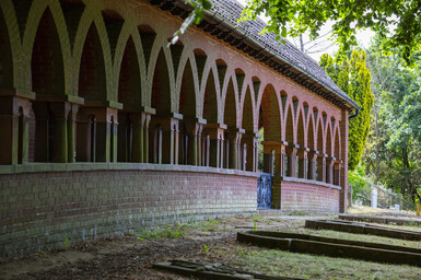 The terracotta cloister is a long low building with a solid wall on one side and columns on the other