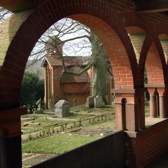 Terracotta corridor with arches, the chapel stands in the background