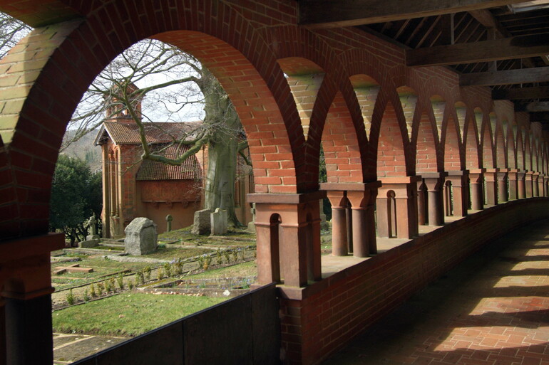 Terracotta corridor with arches, the chapel stands in the background