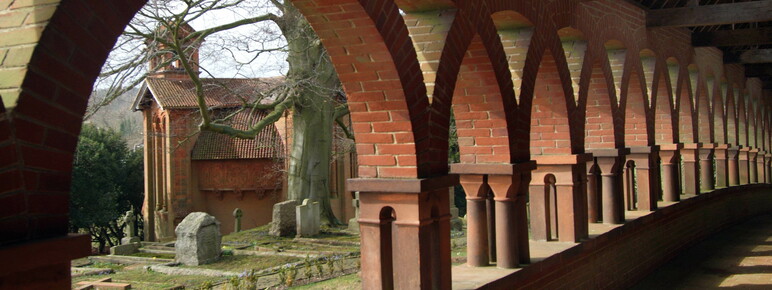 Terracotta corridor with arches, the chapel stands in the background