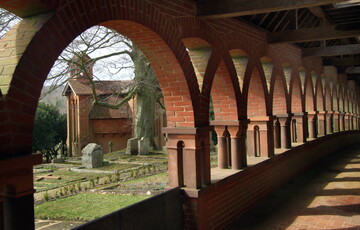 Terracotta corridor with arches, the chapel stands in the background