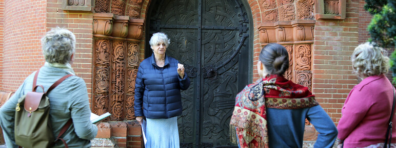A volunteer stands in front of a group by the highly-decorated Watts Chapel black door