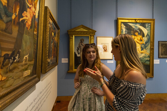 Two visitors discuss a painting in the gallery