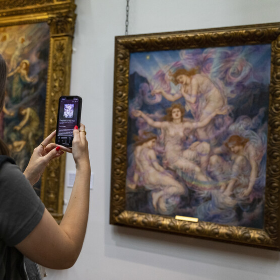 Women holds phone up to artwork in ﻿De Morgan Gallery
