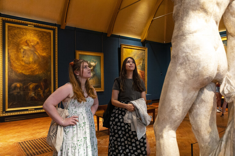 Two visitors look at sculpture in gallery