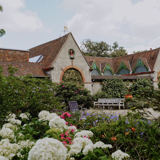 Exterior of Watts Gallery - Artists' Village with summer flowers in the foreground