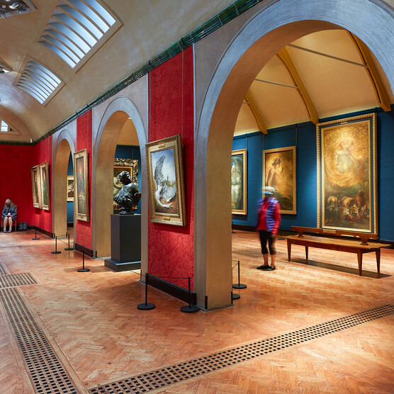 The Historic Galleries with wooden floors and walls. On the walls are framed paintings by George Frederic Watts