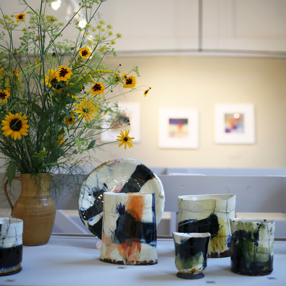White vases with colourful patterns on a table with a vase of yellow flowers