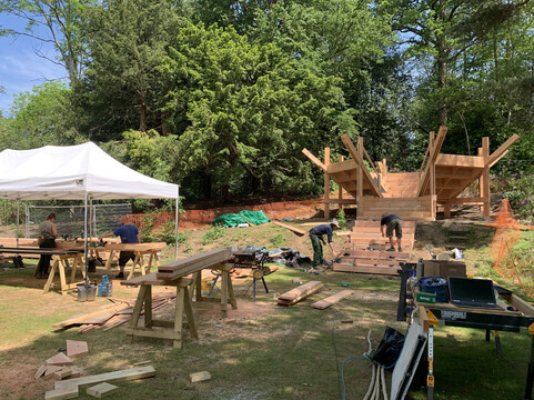 Builders work on wooden amphitheatre with tools and wood around them