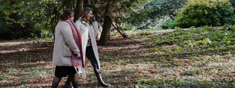 Two young women walk in the grounds at Watts gallery in autumn