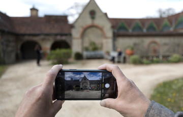 A person holds up their phone to take a photo of Watts Gallery