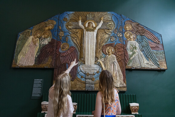 Two visitors point at decorative panel