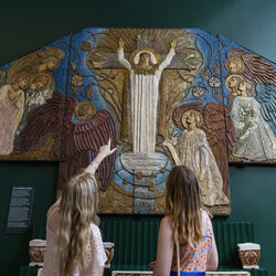 Two visitors point at decorative panel