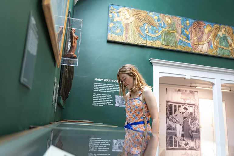 Visitor looks at glass display case in green-walled gallery