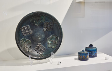 A blue plate and two blue ceramic containers displayed on a shelf