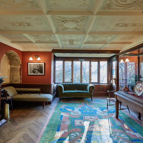 A red room featuring an alcove, patterned rug, decorative white ceiling and green sofa