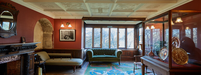 A red room featuring an alcove, patterned rug, decorative white ceiling and green sofa