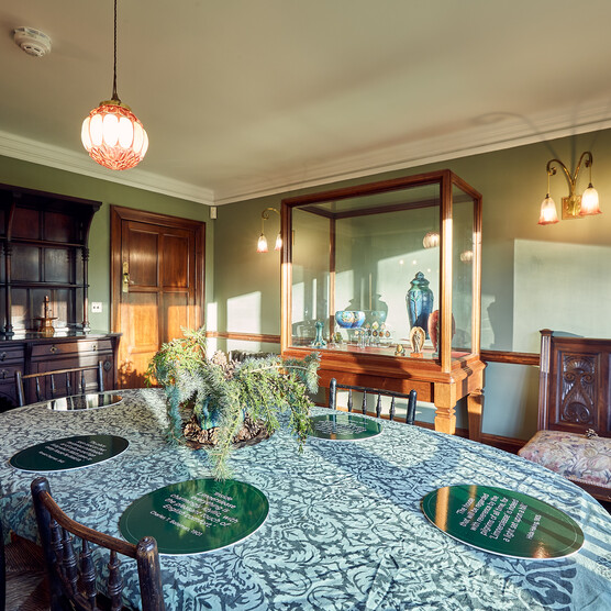 A green room with a dining table, chairs and period furniture