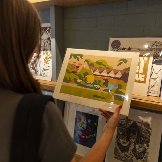 Visitor looks at art print of Watts Gallery building in Shop