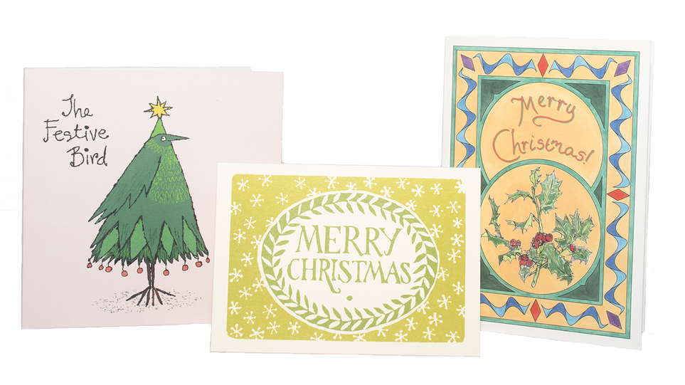 Product photograph of three Christmas cards. The card on the left is an illustration of a bird that looks like a Christmas tree with "A festive bird" written to the left of the illustration. The card in the middle is a block print style card, and has "Merry Christmas" written in green in the centre surrounded by a wreath of leaves. Outside the wreath are snowflakes dotted around the card. The card on the right is a traditional-style card with a holly sprig printed in the middle, with "Merry Christmas" written above the holly sprig.