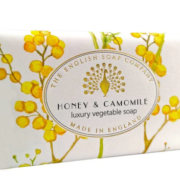A bar of honey and camomile soap in it's packaging featuring yellow camomile illustrations