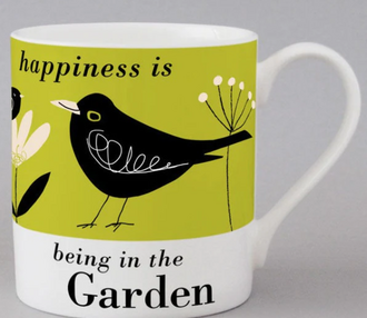 A white mug with a illustration of a blackbird and flowers sitting on a bright green background with the words "Happiness is being in the garden"