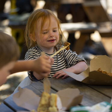 Two children eating cake on a picnic table