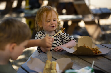 Two children eating cake on a picnic table