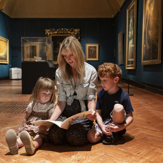 A family reads on the floor in the Historic Gallery