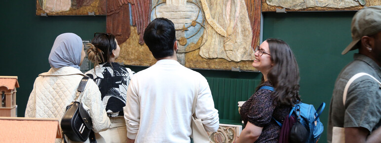 A group of college students look at a large altarpiece in the Mary Watts gallery