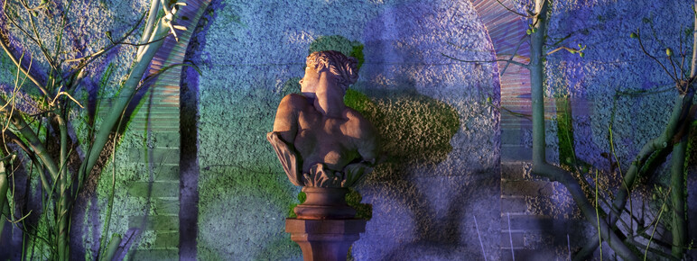 Photo of Clytie bust sculpture at Watts Gallery lit up with purple light in the evening