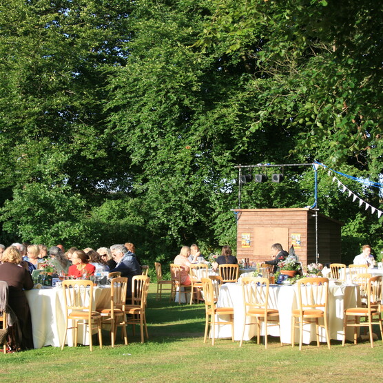 Guests sit at tables outside, laid with white table cloths