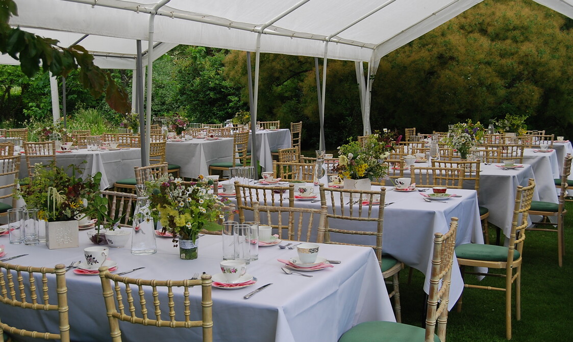 Tables with white table cloths and flowers laid under a gazebo